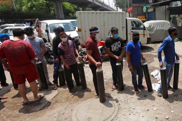 Orang-orang antre untuk mengisi ulang oksigen di tabung silinder di New Delhi, India, pada 23 April. Banyak korban tewas di rumah sakit di ibu kota India di tengah dugaan bahwa pasokan oksigen yang rendah menjadi penyebabnya.