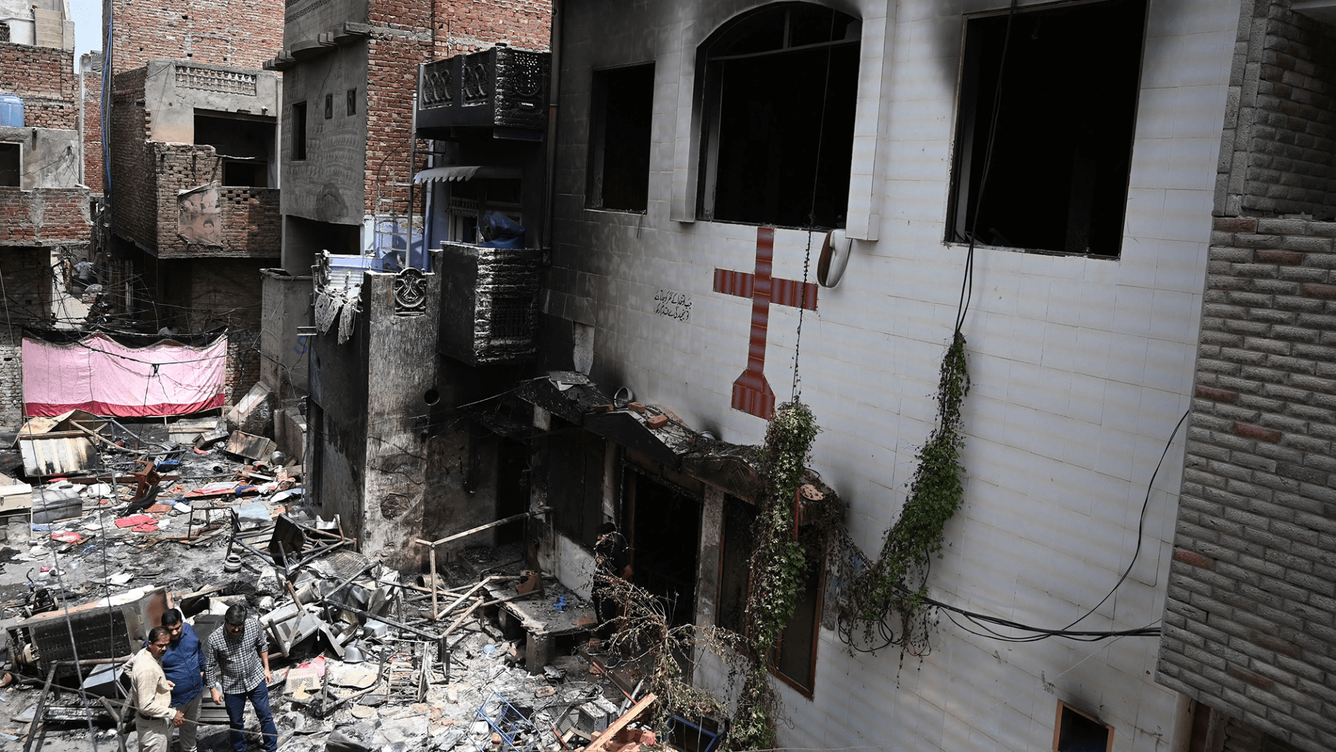 Para pria berdiri di tengah puing-puing di luar Gereja Saint John yang dibakar di Jaranwala di pinggiran Faisalabad pada 17 Agustus 2023, sehari setelah serangan oleh serombongan pria Muslim menyusul tersebarnya tuduhan bahwa umat Kristen telah menodai Al-Qur'an.