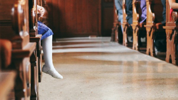 Childs legs sticking out of a pew in a church